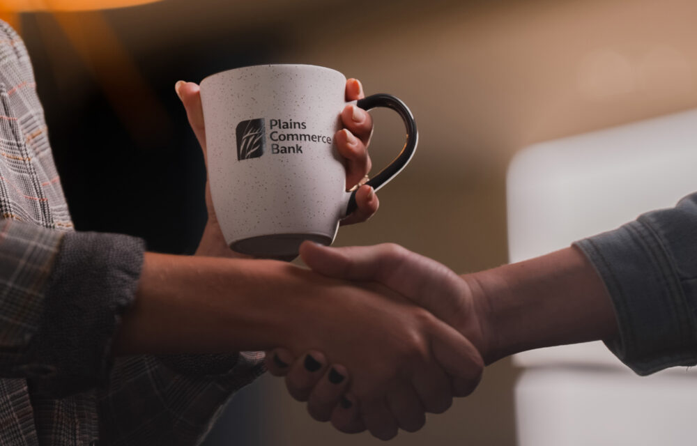 Two people shaking hands, one is holding a PCB coffee cup