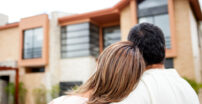 Woman leaning her head on the man's shoulders looking at a home