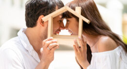 Man and women holding a wood house outline