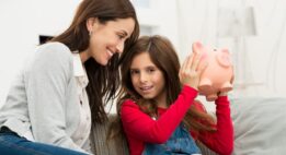 Mom watching her daughter shake her piggy bank