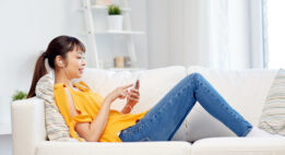 Young woman sitting on a couch with earbuds