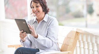 Older Woman On Tablet On Bench