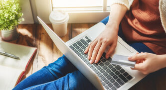 Women sitting on a chair entering her credit card number into her laptop