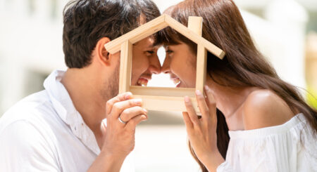 Man and women holding a wood house outline