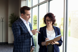 Man pointing to a women's notebook while she writes something down